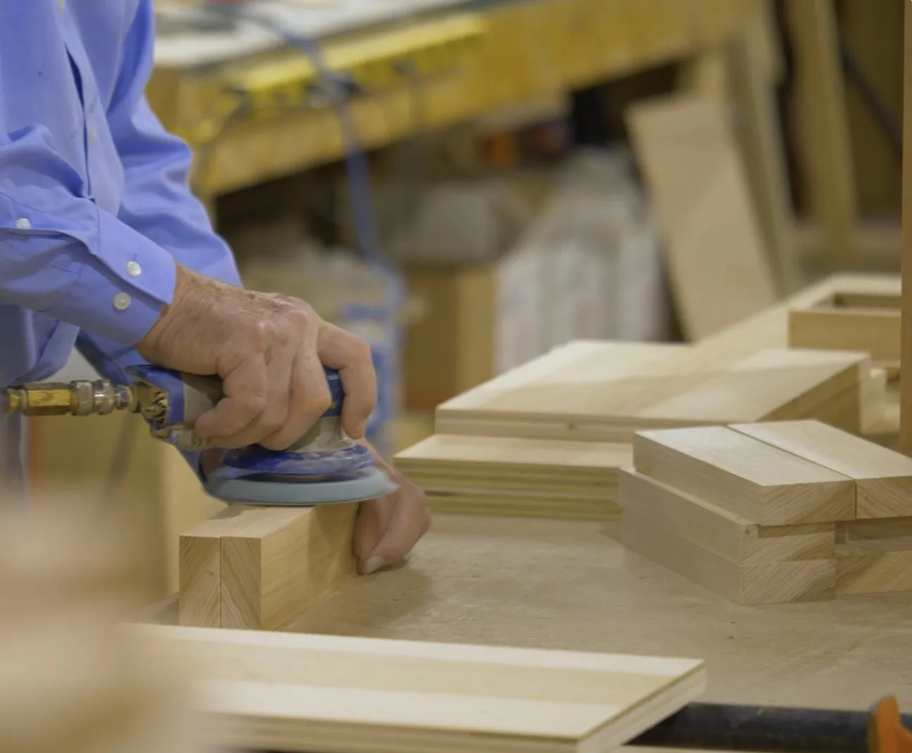 A craftsman hand-sanding a solid hardwood component in the workshop