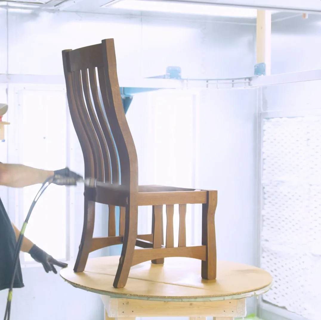 A hardwood dining chair being hand-finished in the spray booth